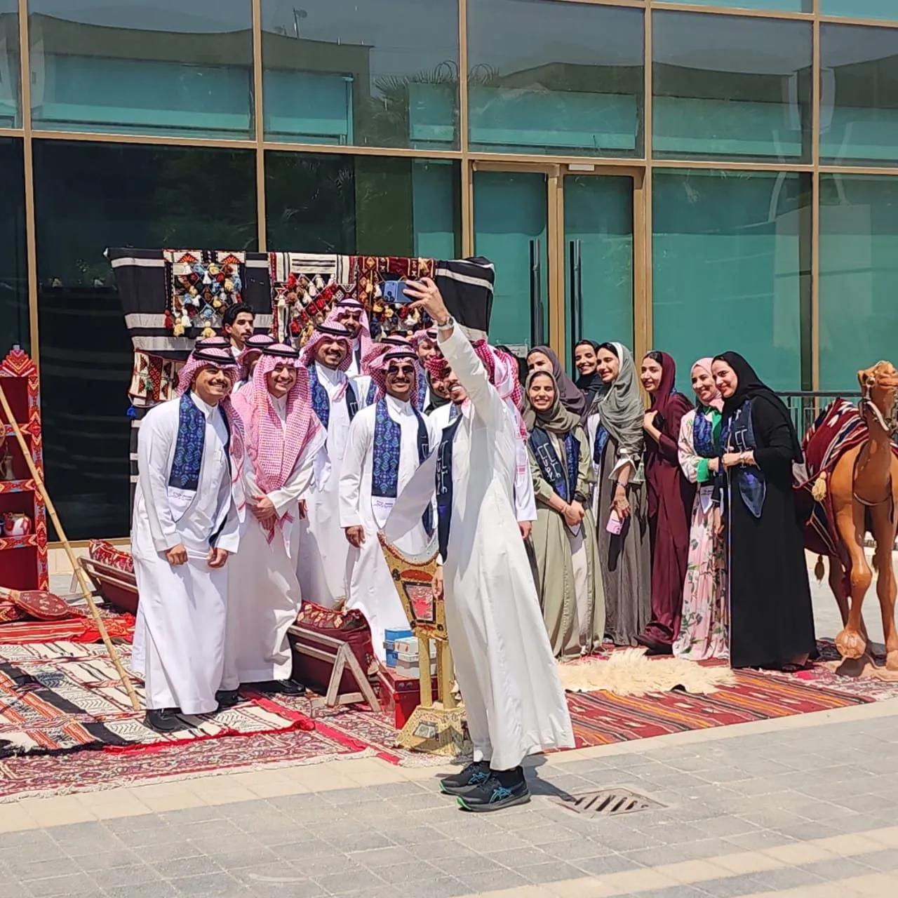 Staff group in national dress posing at majlis with camel