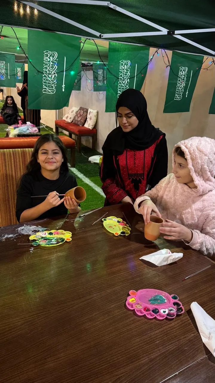 Girls painting pottery, one smiling