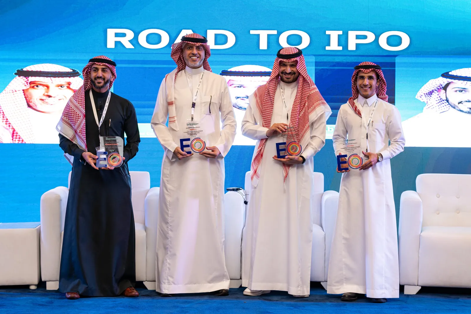 Four smiling speakers holding EO awards on stage