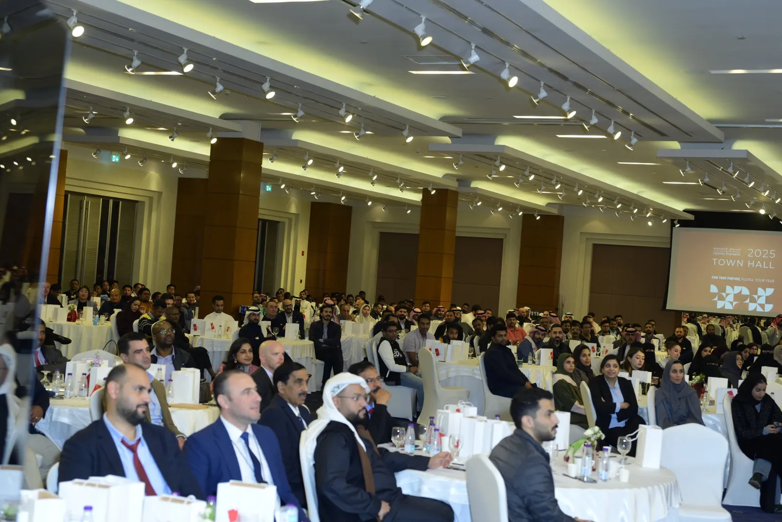 Full ballroom audience facing branded 2025 Town Hall screen